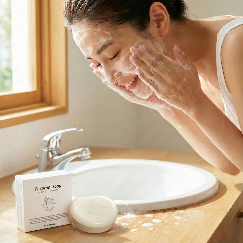 Fucoran Fucoidan Soap – woman washing face with soap, smiling, product on bathroom counter